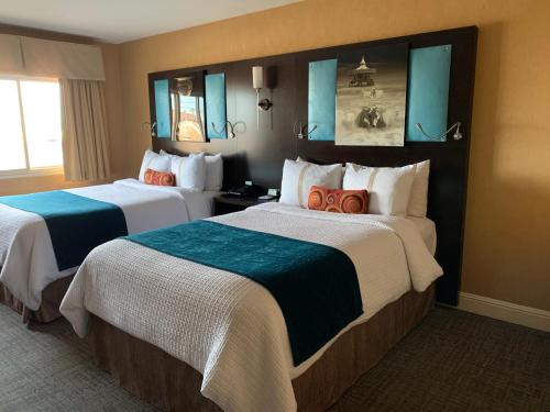 米尔布雷The Dylan Hotel at SFO的两张位于酒店客房的床,配有蓝色镜子