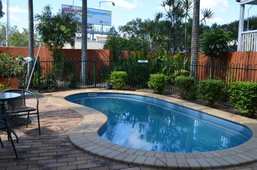 布里斯班Airport Motel Brisbane的一个带砖砌庭院和围栏的小游泳池