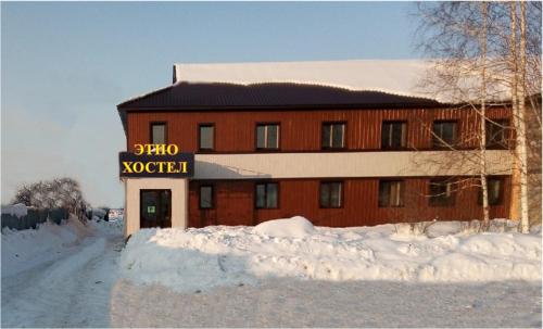 戈尔诺-阿尔泰斯克EtnO Hostel的雪中标有标志的建筑物