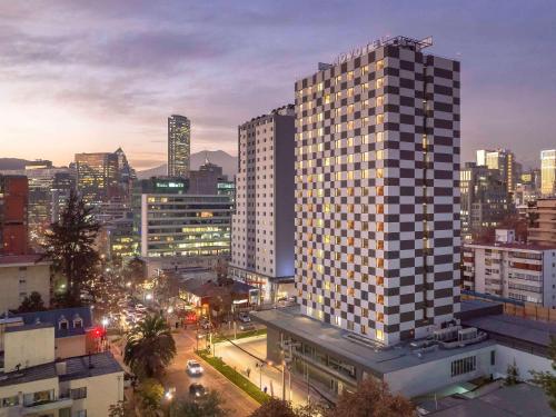 圣地亚哥Novotel Santiago Providencia的夜晚在城市的高楼