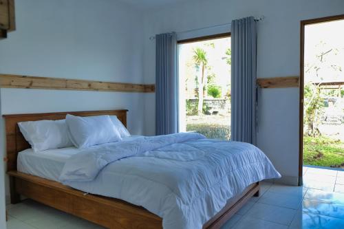 BaturajaHost @ Volcano的一间卧室配有一张蓝色墙壁的床和一扇窗户