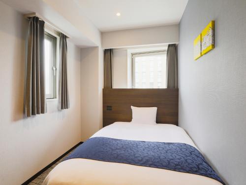 东京池袋永安国际酒店的一间小卧室,配有床和2个窗户