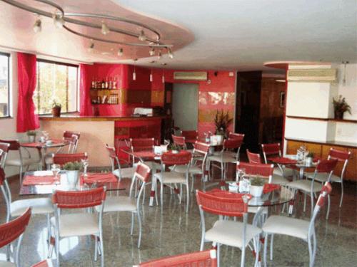 马卡埃罗莎马尔酒店的一间带桌椅和红色墙壁的餐厅