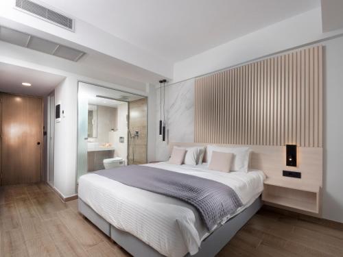 罗德镇雅典娜酒店 的一间带白色大床的卧室和一间浴室