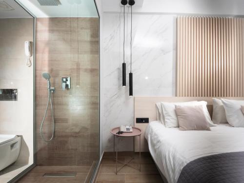 罗德镇雅典娜酒店 的一间卧室设有淋浴、一张床和一个浴缸。