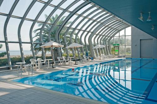 淡路The Gran Resort Elegante Awajishima的一座带玻璃天花板的建筑中的游泳池