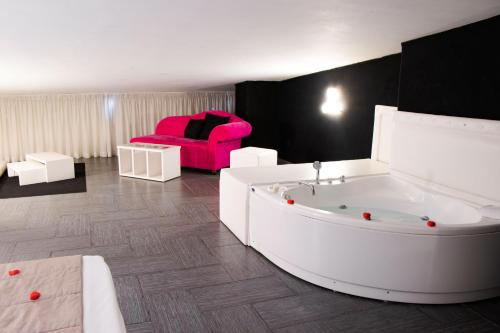 卡索里亚马萨尼尔洛豪华酒店的一间带浴缸和粉红色椅子的客厅