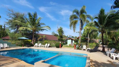 奥南海滩Mild Garden View Resort的一个带白色椅子和棕榈树的游泳池