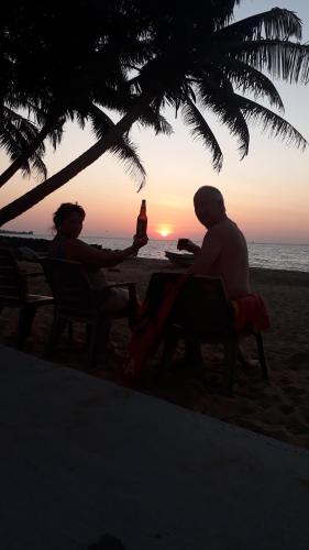 尼甘布阿尼齐亚海滨别墅的两人坐在海滩上欣赏日落