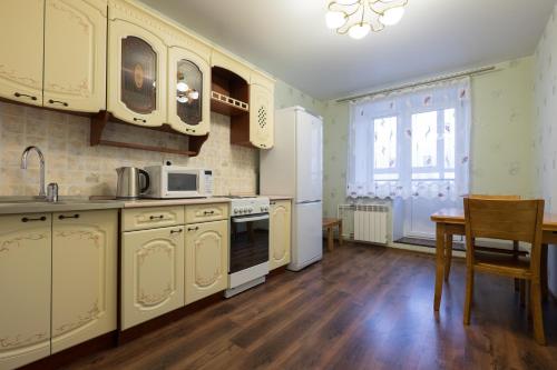 托木斯克OK! Советская, 69 №1的厨房配有白色橱柜、桌子和窗户。