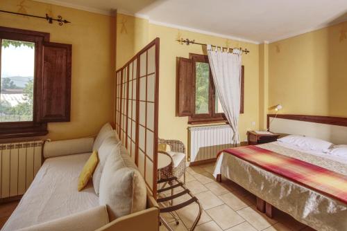 Peveragno卡希纳拉科门达酒店的一间卧室配有一张床、一张沙发和窗户。