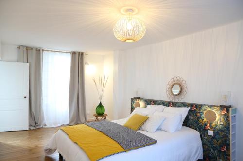 May-sur-OrneLa maison d'à côté的一间卧室配有一张床和一个吊灯