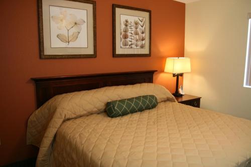 费耶特维尔Affordable Suites - Fayetteville/Fort Bragg的卧室配有一张床,墙上挂有两张照片