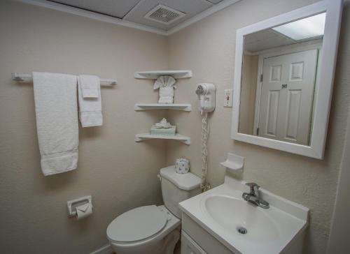 沃尔顿堡滩码头海湾度假酒店的一间带卫生间、水槽和镜子的浴室