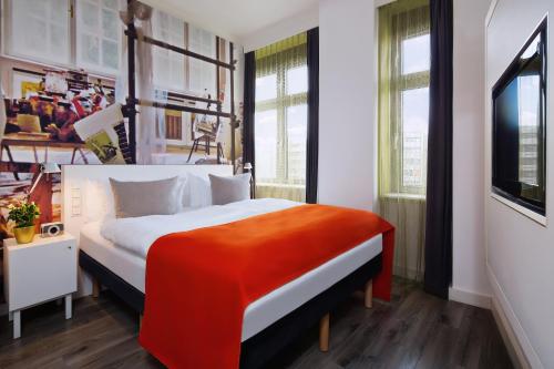 柏林Hotel Indigo Berlin – Ku’damm, an IHG Hotel的一间卧室配有一张带橙色毯子的床