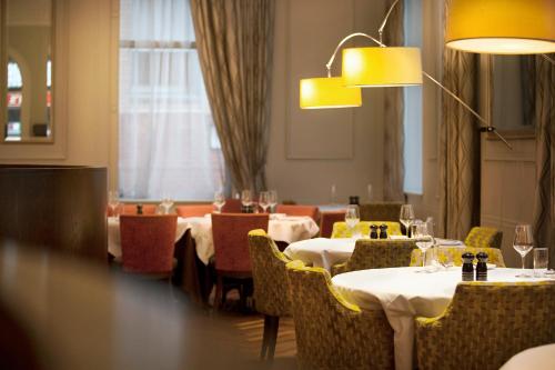 格拉斯哥靛蓝格拉斯哥酒店的用餐室配有桌椅和灯光