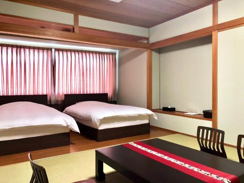 高知高砂酒店 的一间卧室配有两张床和一张桌子及椅子