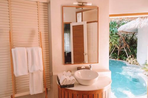 华欣Kundala Beach Resort Hua Hin的游泳池旁的浴室设有水槽和镜子