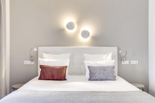 库尔布瓦Hotel Courseine的一张白色的床,上面有两个枕头