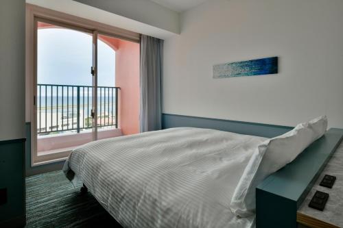 北谷町Lequ Okinawa Chatan Spa ＆ Resort的一间卧室设有一张床和一个大窗户