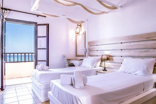 赫索尼索斯Porto Greco Village Beach Hotel的白色客房的两张床,设有窗户