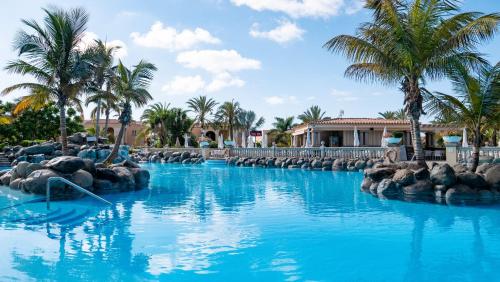 马斯帕洛马斯棕榈绿洲玛斯帕洛玛酒店的拥有蓝水和棕榈树的度假村的游泳池