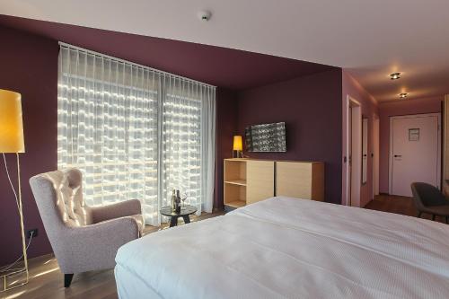 苏斯坦Links Leuk Golfresort的卧室配有床、椅子和窗户。