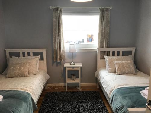 东基尔布赖德Flat Five, 212 Eaglesham Road, East Kilbride, Glasgow的带窗户的客房内设有两张单人床。