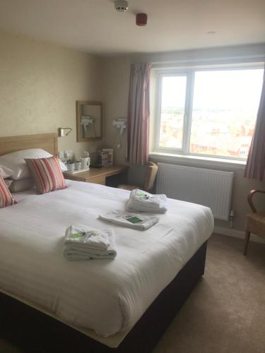 布里德灵顿君主酒店的一间卧室配有一张大床和毛巾