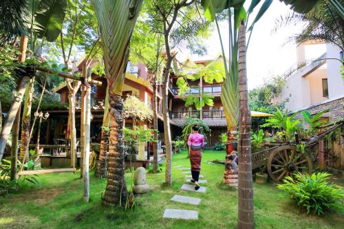 景洪市享自在独立设计度假艺墅（免费接送机）的一位妇女穿过种有棕榈树的花园