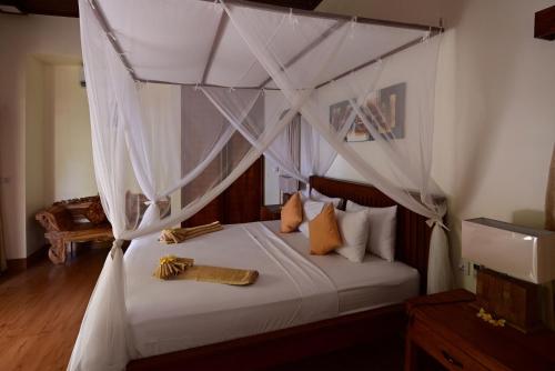 特贾库拉Bahari Villa Tejakula的卧室配有带白色床单和枕头的天蓬床。