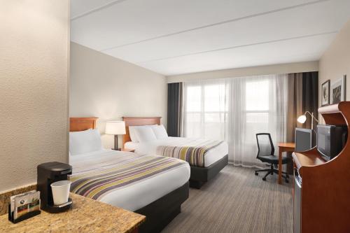 奥兰多Country Inn & Suites by Radisson, Orlando Airport, FL的酒店客房配有两张床和一张书桌