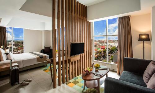 日惹KHAS Tugu Hotel Yogyakarta的酒店客房配有床、沙发和电视。