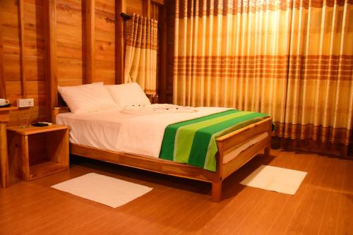 达瓦拉维Wild Lake Side的一间卧室配有一张带绿色和白色毯子的床