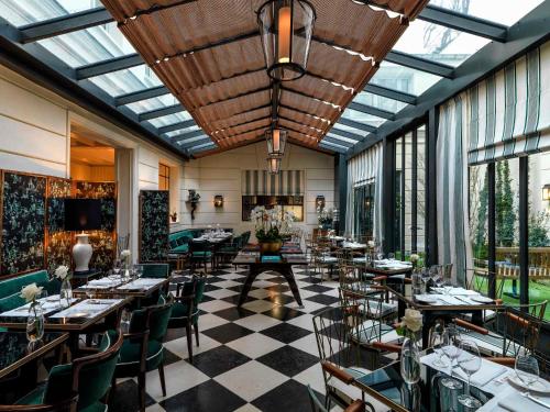 巴黎J.K. Place Paris的一间设有桌椅的餐厅,位于带窗户的房间内