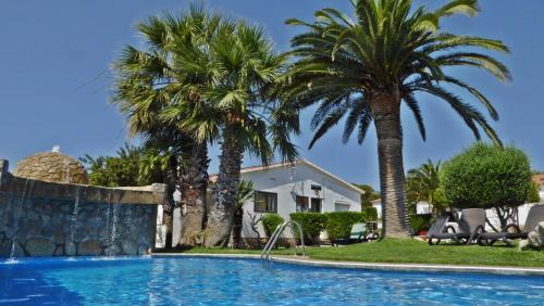 霍斯皮塔勒·德尔英福BUNGALOW-PARK LAS DOS TARTANAS的一座棕榈树游泳池和一座房子
