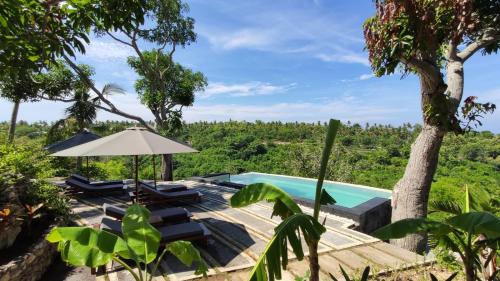 珀尼达岛Tanah Damai Hotel的享有带椅子和遮阳伞的游泳池的景致。