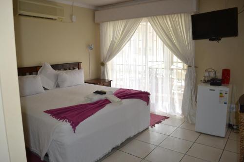 兰斯堡Kamogelo Guest House的一间卧室设有一张大床和一个大窗户