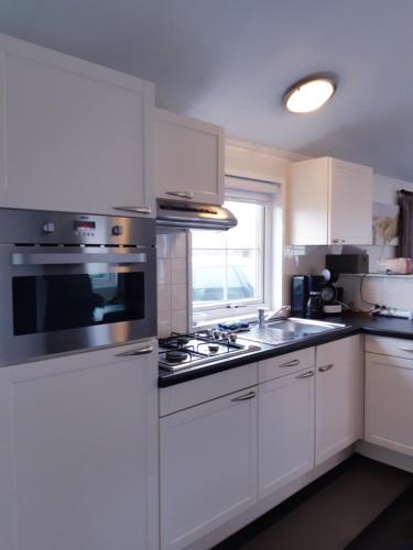 德哈恩Zeepark Haerendyke的厨房配有白色橱柜和炉灶烤箱。