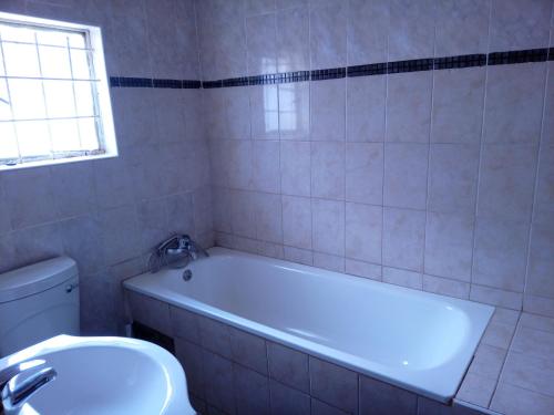 卢萨卡Royal Olympia Lodge Lusaka的带浴缸、卫生间和盥洗盆的浴室