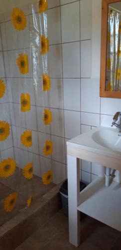 TanetaneMango Garden Cottages的墙上设有水槽和黄色鲜花的浴室