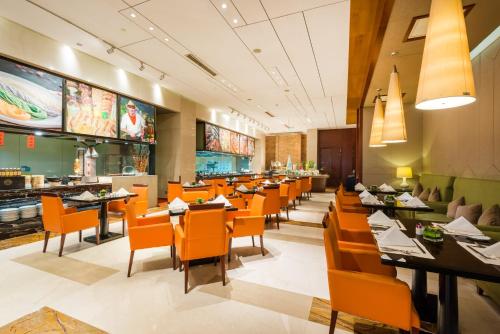 襄阳襄阳富力皇冠假日酒店 的餐厅内带橙色椅子和桌子的用餐室