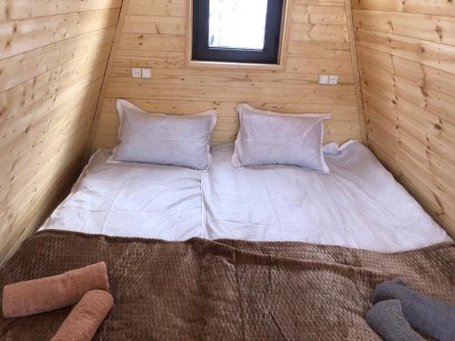 梅斯蒂亚Paradiso Mestia的木制客房的一张床位,配有两个枕头