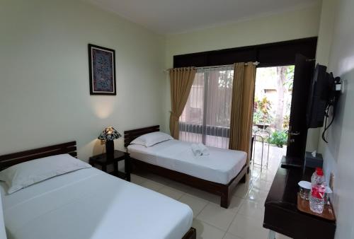 日惹Puri Pangeran Hotel的一间卧室设有两张床和窗户。