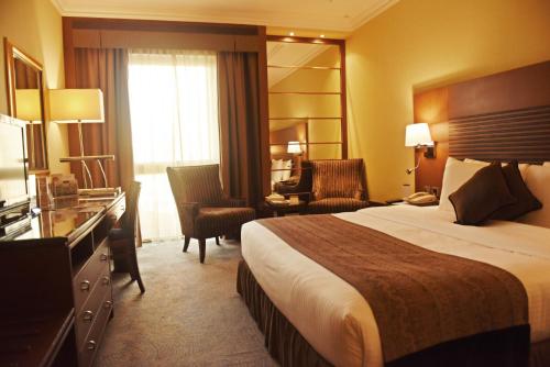 麦纳麦巴林金色郁金香酒店的酒店客房,配有一张床、一张桌子和椅子