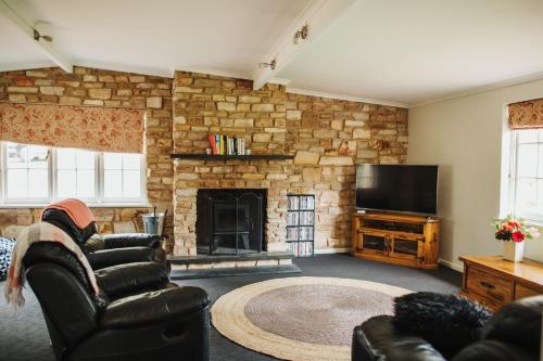 克莱尔Cooke Cottage的客厅设有石制壁炉和电视。