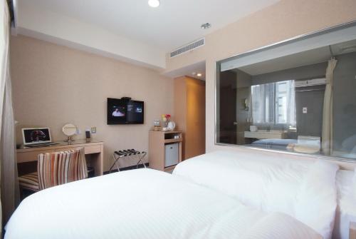 台中市豪爵大饭店台中馆的卧室设有白色的床和大窗户
