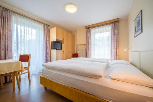 多比亚科Hotel Nocker的卧室配有一张白色大床、桌子和窗户