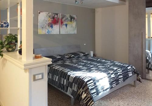 博洛尼亚L'Appartamentino的卧室配有一张床,墙上挂有绘画作品