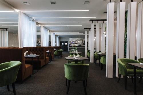 伊热夫斯克Panorama Hotel的用餐室配有桌子和绿色椅子
